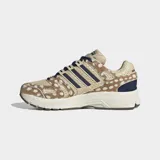 Championes Adidas Adistar Control 5 con diseño retro inspirado en los años 2000. Presenta parte superior de malla transpirable color beige con estampado animal print de leopardo, capas superpuestas de cuero peludo, las tres tiras características de la marca en azul marino y cordones oscuros.