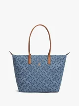Cartera tote Tommy Hilfiger confeccionada en tejido denim azul con estampado geométrico de monogramas. Cuenta con asas superiores de cuero sintético marrón, cierre superior de cremallera y herrajes metálicos dorados con el monograma de la marca en el frente.