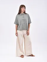 Camisa de manga corta, color rojo, con cuello camisero y botones frontales. Presenta dos bolsillos de parche en el pecho.