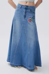 Falda larga de jean celeste, corte evasé, con tiro medio y bordado floral en la parte superior.