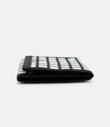 Billetera plegable de poliéster con estampado cuadriculado en blanco y negro. Cierre con velcro y múltiples compartimentos interiores.