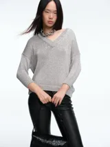 Sweater de punto con brillo, de corte relajado y escote en V. Presenta hombros caídos y mangas largas con puños acanalados.