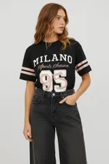 Remera de algodón de corte holgado con cuello redondo y mangas cortas. Presenta un diseño de estilo deportivo con franjas blancas en las mangas y una estampa frontal con temática de béisbol y un tigre.