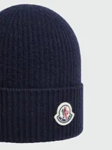 Gorro tipo beanie de punto acanalado en color azul marino, con parche del logo de la marca en la parte frontal.