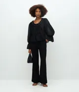 Pantalón de sastrería wide leg en crepé negro, de cintura alta con cierre delantero y botón, con bolsillos traseros decorativos.