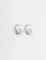 Aros tipo argolla de acero quirúrgico con diseño de superficie irregular y acabado brillante.