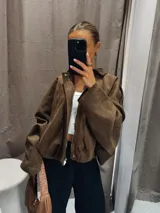 Campera tipo bomber de gamuza en color marrón, con cuello clásico, mangas largas amplias y ruedo elástico que genera un efecto fruncido.