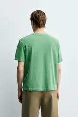 Camiseta de corte regular con cuello redondo, manga corta y bolsillo plastrón en el pecho. Presenta un acabado de color verde con efecto lavado.