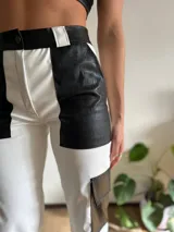 Pantalón de cuero sintético blanco y negro, de corte recto, con bolsillos laterales y traseros.