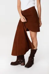 Falda de cuero marrón con diseño asimétrico, presenta un detalle de lazo frontal drapeado que crea una caída lateral más larga.
