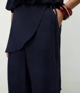 Pantalón modelo aladim confeccionado en jacquard de viscosa, con diseño floral en relieve, cintura elástica y superposición asimétrica en el delantero que forma un canesú redondeado.