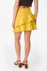 Minifalda amarilla confeccionada en lino italiano, de corte en A, con diseño de doble volado escalonado y detalles de terminación con bordado calado.