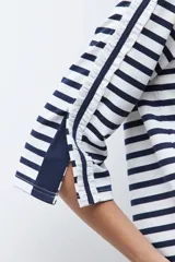 Remera de manga tres cuartos con diseño a rayas horizontales en azul marino y blanco. Presenta un detalle de volados laterales en las mangas y cuello redondo.