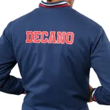 Campera tipo bomber azul marino con cierre frontal de botones a presión. Presenta el logo de Umbro bordado en el pecho derecho, el escudo del Club Nacional de Football en el pecho izquierdo, el año 1899 bordado debajo del escudo y detalles con los colores del club en cuello, puños y ruedo. Incluye parches laterales conmemorativos.