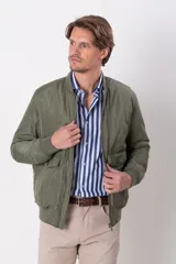 Campera bomber verde militar de nylon, con cuello y puños de algodón, cierre frontal y bolsillos con solapa y botón.