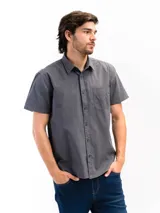 Camisa de manga corta color celeste claro, confeccionada en algodón, con cuello clásico y un bolsillo de parche en el lado izquierdo del pecho.