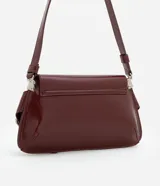 Cartera baguette Satinato pequeña de color negro, confeccionada en poliuretano. Presenta una solapa frontal con cierre de botón a presión, correa ajustable para el hombro y detalles decorativos de hebillas con argollas metálicas plateadas en los laterales.