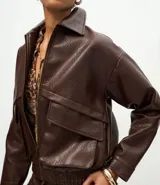 Campera de cuero sintético color marrón oscuro, con cuello clásico, cierre frontal metálico, dos bolsillos frontales amplios con solapa y ruedo con elástico.