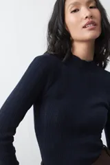 Polera de tejido de punto con textura calada y acanalada, de silueta entallada, cuello alto y manga larga.