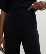 Pantalón de corte recto confeccionado en tejido de punto con cintura elástica. Presenta un diseño básico y versátil de tiro medio.