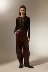 Pantalon de eco-cuero con diseño barrel, de tiro alto y corte holgado. Cuenta con bolsillos laterales y cierre frontal con botón.