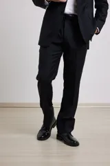 Traje de corte clásico compuesto por saco de dos botones y pantalón de vestir a juego. El saco presenta solapas tradicionales y bolsillos con solapa, mientras que el pantalón tiene un corte recto y formal.