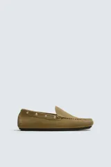 Mocasín de vestir fabricado en piel con acabado serraje, con detalle de tachas metálicas en el lateral y suela de goma.