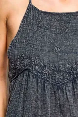 Top camisero negro de algodón sin mangas, con escote cuadrado y tirantes ajustables. Presenta bordados florales en el corpiño y en el bajo, corte imperio fruncido y silueta fluida.