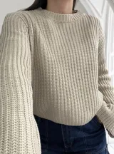 Sweater beige de punto grueso con cuello redondo y mangas largas.