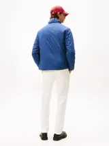 Campera acolchada de hombre, color azul marino, con cuello alto y cierre frontal de cremallera. Presenta bolsillos laterales con cierre y el logo de Tommy Hilfiger bordado en el pecho.