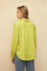 Camisa blanca de manga larga con textura arrugada, cuello camisero y botones frontales. Presenta un corte holgado y puños anchos con tres botones.