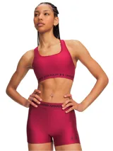 Top deportivo Under Armour Crossback Mid de color fucsia, con diseño cruzado en la espalda y banda elástica inferior con el nombre y logo de la marca.