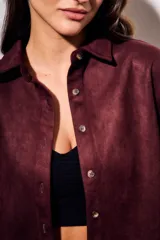 Camisa color marrón de gamuza sintética, de corte recto, con cuello clásico, cierre frontal con botones y mangas largas.