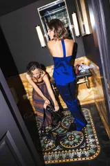 Vestido largo de punto con diseño a rayas horizontales en tonos azules, marrones y mostaza, con destellos de lurex. Presenta cuerpo ajustado con tirantes finos y falda larga de gran vuelo.