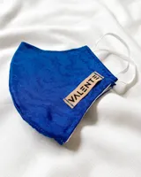 Tapabocas de tela color azul con estampado abstracto y etiqueta con la marca VALENTE.