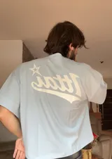 Remera rosa de corte holgado con estampado trasero de la palabra "Ittai" en blanco con una estrella.