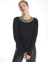 Buzo tejido de punto color negro, con cuello redondo decorado con apliques de brillos y mangas largas.