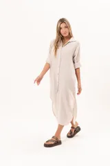 Vestido camisero largo de lino color beige, con silueta relajada, abotonado al frente, cuello camisero, mangas regulables y tajos laterales.