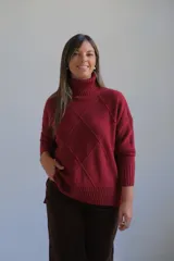 Polerón de cuello alto con diseño de rombos en relieve, mangas largas con puños acanalados y ruedo asimétrico con aberturas laterales.