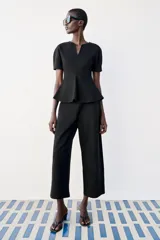 Top peplum confeccionado en hilatura de algodón de color bordó, con escote en V pronunciado, mangas cortas abullonadas y bajo con vuelo.