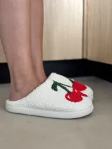 Pantuflas blancas con interior de felpa y estampado de cerezas rojas con hojas verdes.