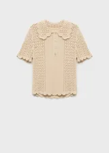 Jersey de punto calado en color beige, con diseño de manga corta, cuello polo con terminación en ondas y cierre frontal de botones.