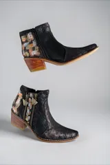 Botas de caña corta de cuero negro jaspeado, pintadas a mano con arte en tonos dorados, plateados y marrones en la parte trasera. Cuentan con doble cierre lateral con tiradores metálicos personalizados, puntera fina y taco cuadrado de madera.