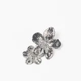 Par de caravanas de metal plateado con diseño de doble flor superpuesta, con acabado texturizado y brillante.