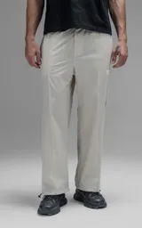 Pantalón de corte oversize confeccionado en microfibra técnica con sutil elasticidad. Presenta cintura elástica, bolsillos laterales y un bolsillo cargo con cierre de broche snap. Incluye un sistema de elásticos con tancas en los tobillos para regular la apertura y modificar la silueta.