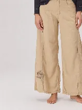 Pantalon de corte ancho y holgado, confeccionado en mezcla de algodón y lyocell. Presenta un diseño fluido con costuras verticales decorativas y bordado sutil en la pierna.