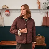 Chaqueta de sherpa color crema con estampado floral en tonos marrones, amarillos y verdes. Tiene cuello camisero y ribete de pana marrón.