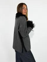 Saco de punto acanalado en color beige, con cierre frontal y detalles de piel sintética en el cuello y los puños.