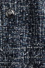 Vestido corto de tejido bouclé en tonos azul marino y blanco, con cuello redondo, manga corta y cierre frontal con botones metálicos decorativos. La falda tiene un corte acampanado con vuelo.