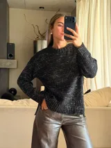 Sweater de punto con silueta holgada y cuello a la base, confeccionado en una mezcla de algodón y lurex que le otorga un acabado brillante. Presenta un diseño con aberturas laterales en el ruedo y puños acanalados.